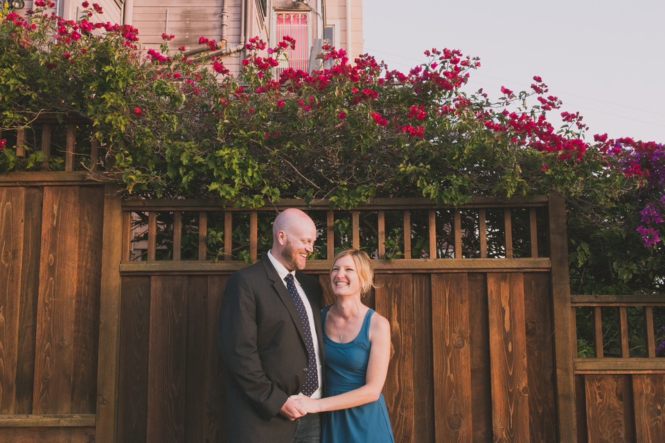 couple standing along a wooden fench in the mission district of san francisco california